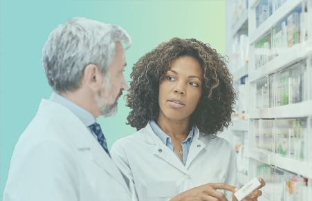 Two pharmacists next to medications discussing one item in particular