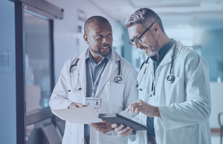 Two male doctors discussing items on clipboard